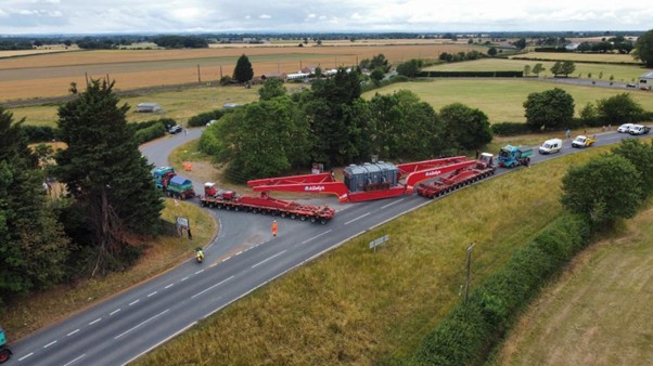 Photograph of the supergrid transformer delivery making its final turn onto Overton Road from the A19. Behind the delivery vehicle there is a convoy of vehicles.  