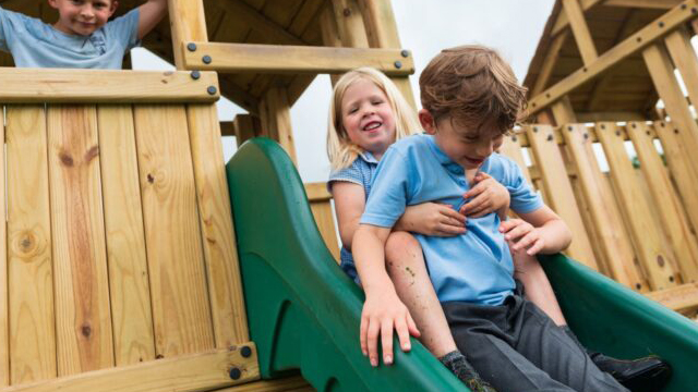 Young girl and boy sitting at the top of a slide