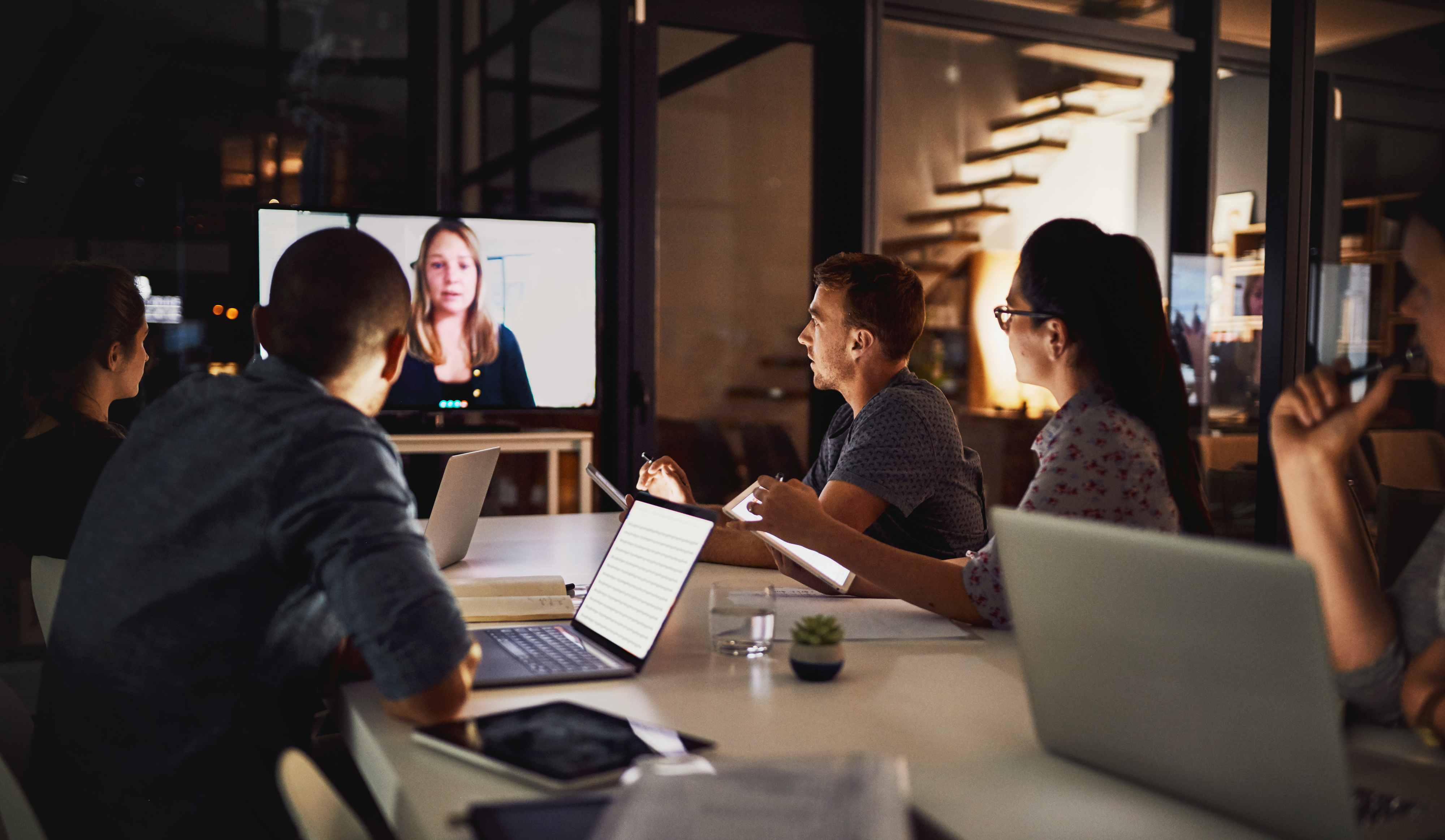 A group of individuals sitting around a table in front of a conference call screen