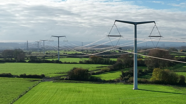 T-pylons and overhead electricity lines across green fields
