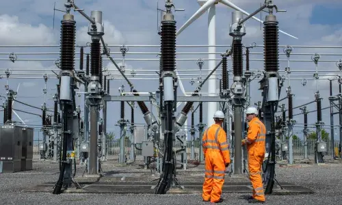 Two engineers wearing orange high-vis overalls and hard hats at Bicker Fenn Substation