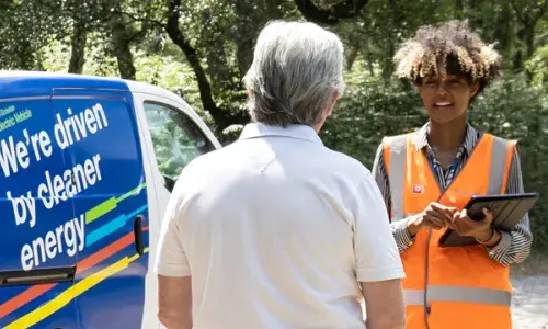 We're driven by cleaner energy - woman with clipboard talking to a man next to an electric van