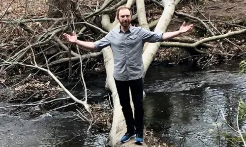 Gideon Banner standing on a log across a river used for National Grid's green collar jobs story