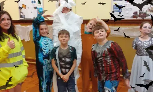 Children dressed in Halloween outfits with superimposed bats in the foreground