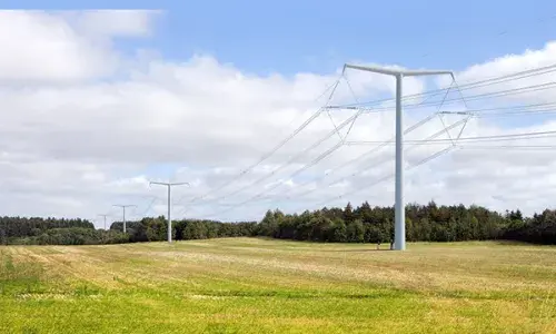 New electricity T-pylons and overhead lines running across a field with woods in the background