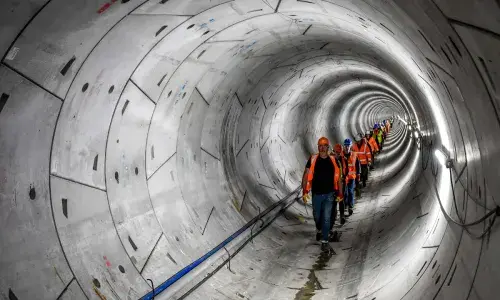 A line of people wearing hard hats and high-vis walking through the Humber Tunnel - used for the National Grid story 'Celebrating the completion of the Humber Tunnel'