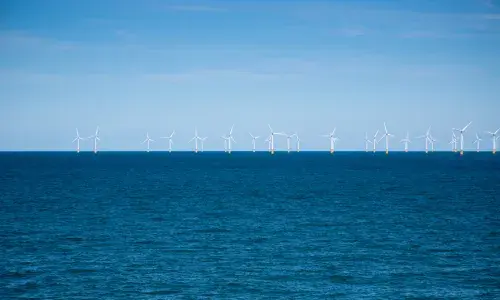 Wind farm in the distance at sea for National Grid 'Green loan speeds race to net zero' story