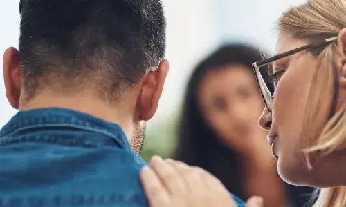 Woman talking to a man with her hand on his shoulder