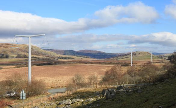An overview of Lake Bala under a cloudy blue sky with electricity masts extending into the background