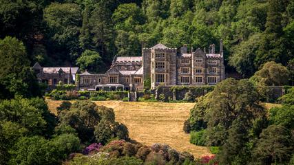Beautiful old stone manor building in front of yellow field with woods behind