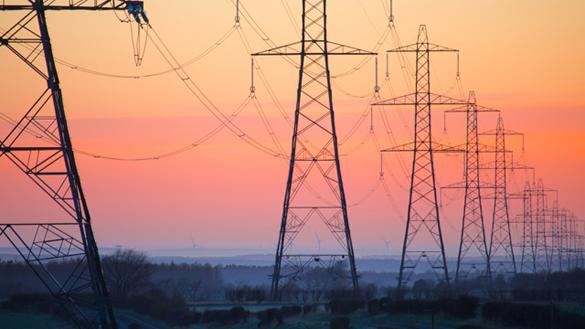 EnergyExplained_ElectricityPylons_585x329.jpg Row of lattice electricity pylons against an orange sky