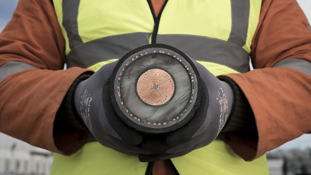 InsideAnInterconnectorCable_640x360.jpg Person wearing a high-vis vest and safety gloves holding a sample of an interconnector cable